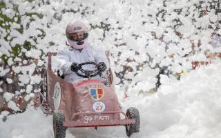 The soapbox from St Joseph's College driving through the foam cloud