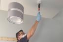A member of Essex County Fire and Rescue Service's Home Fire Safety team testing a smoke alarm