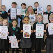 Textile artist Ellen Jackson and children from Dunmow St Mary's Primary School with drawings and the quilt squares made by community volunteers