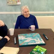 Kevin, Margaret and Maisie the schnoodle enjoy a game of Scrabble at Mountfitchet House